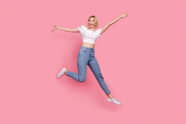 Full length photo of attractive girl jumping energetic have fun hands up running big sale model promoter isolated on pink color background. - Zdjęcie, obraz