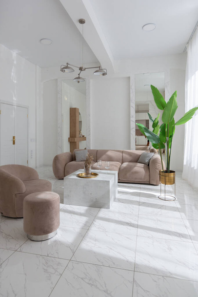 living room with soft beige furniture in a light luxury interior design of a modern apartment in a minimalist style with marble trim and huge windows. daylight inside. - 写真・画像