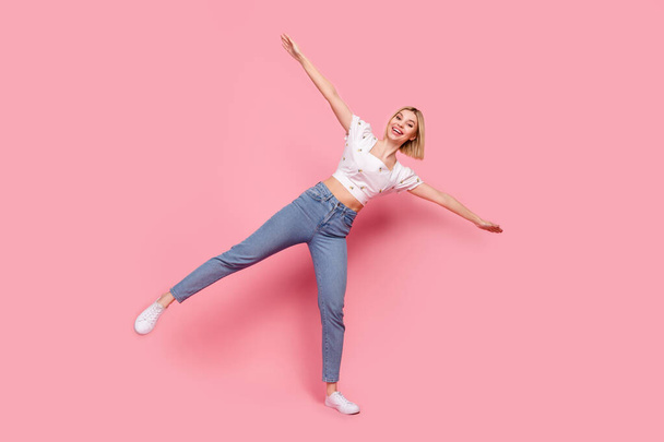 Full size photo of funny young girl summertime party stylish dressed white top denim jeans hold balance isolated on pink color background. - Photo, Image