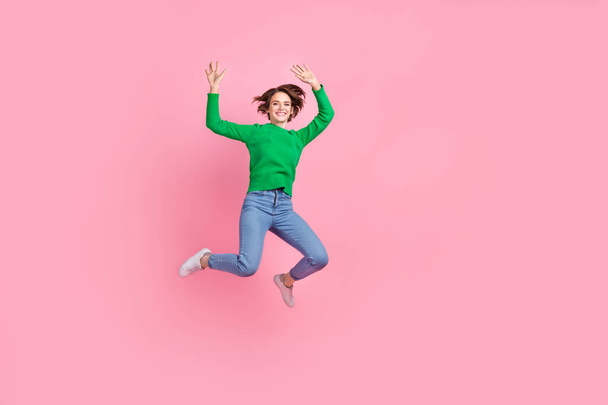 Full length photo of excited cheerful girl dressed green sweater jumping high empty space isolated pink color background. - Photo, image