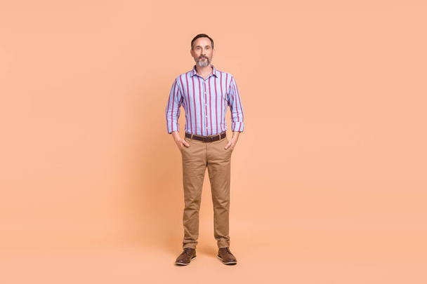 Pleine longueur photo de la personne sérieuse avec barbe grise habillée chemise colorée bras debout dans des poches isolées sur fond de couleur pastel. - Photo, image
