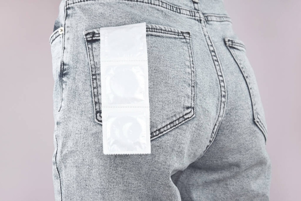 ジーンズのポケットにコンドーム。感染を防ぐ。世界エイズデー。性的健康の概念. - 写真・画像