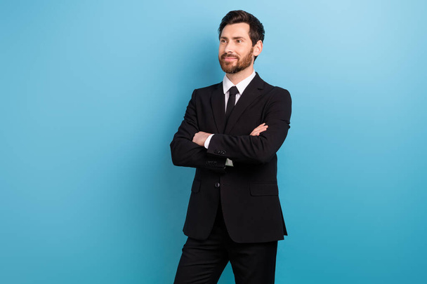 Photo of thoughtful confident entrepreneur guy dressed black suit arms folded looking empty space isolated blue color background. - Fotó, kép