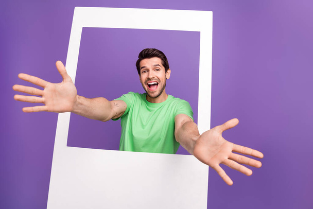 Photozone memories picture cadre of young funny guy paper frame shooting friendly event hugs followers isolated on violet color background. - Fotoğraf, Görsel