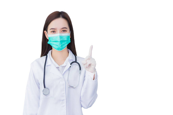 Femme asiatique médecin qui porte un masque médical, gant en caoutchouc pour protéger la santé pointe vers le haut pour présenter quelque chose tout en étant isolé sur fond blanc. - Photo, image