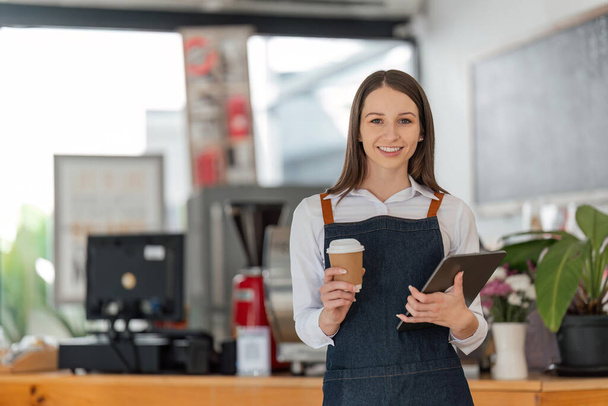 Startup successful small business owner sme beauty girl stand with tablet in coffee shop restaurant. Portrait of asian woman barista cafe owner. SME entrepreneur seller business concept. - Fotó, kép