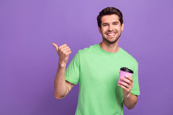 Photo of funny young advertiser promo picture guy coffee takeaway morning teatime point finger mockup isolated on violet background. - Fotoğraf, Görsel