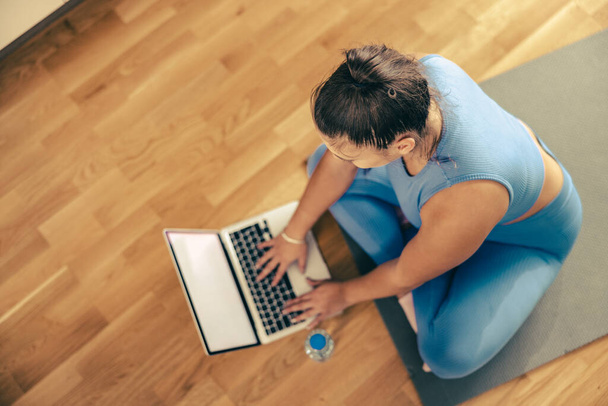Top pohled na mladou ženu pomocí notebooku při cvičení ve fitness doma. - Fotografie, Obrázek