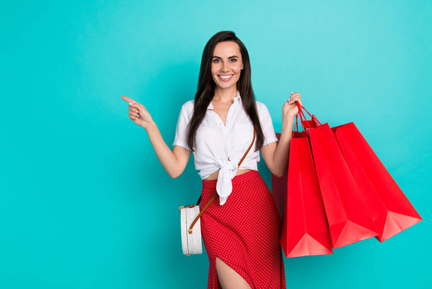 Photo of cute adorable girl wear white tied shirt handbag holding bargains pointing empty space isolated teal color background. - 写真・画像