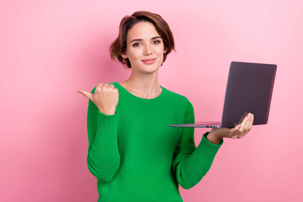 Photo of positive pretty lady wear green pullover pointing thumb empty space working modern device isolated pink color background. - Foto, immagini