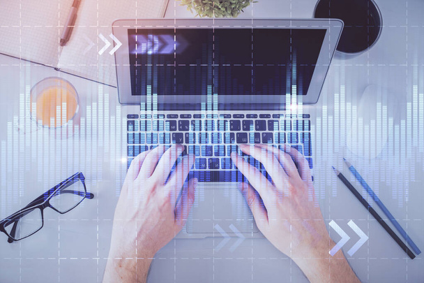 Double exposure of man's hands typing over laptop keyboard and forex chart hologram drawing. Top view. Financial markets concept. - 写真・画像