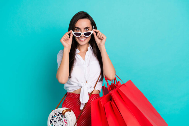 Photo of pretty adorable lady dressed white crop top purse hands eyewear holding red shoppers empty space isolated turquoise color background. - Foto, Bild