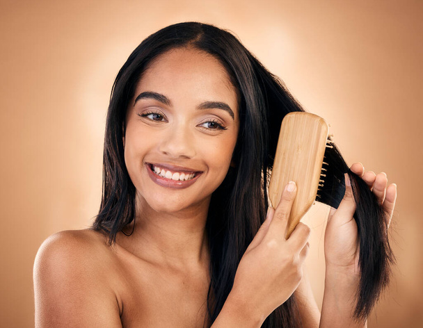 Hair care, brush and happy woman with beauty isolated on a brown background in studio. Salon, smile and model with a wood grooming product for natural aesthetic, hairdresser or hairstyle for wellness. - Fotografie, Obrázek