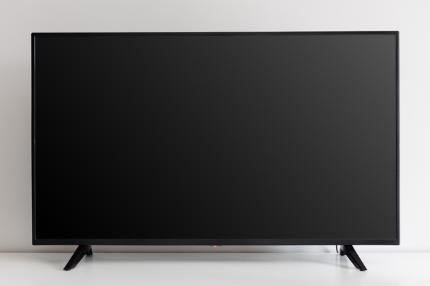 Blanco zwart tv scherm op witte commode tegen witte muur - Foto, afbeelding