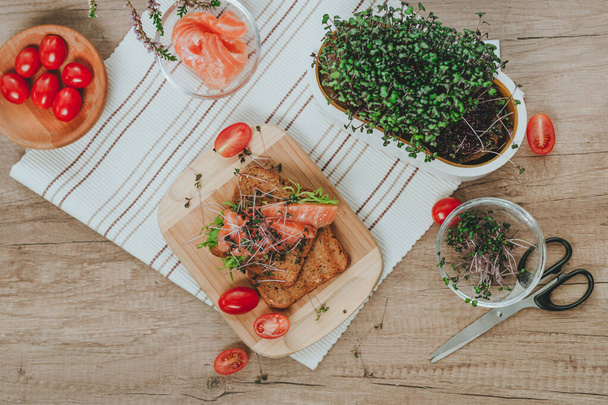 鮭とサンドイッチ,木製の背景に大根とトマトのマイクログリーン.自家製ビタミン食品のアイデア。選択的焦点. - 写真・画像
