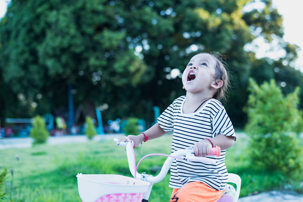 Wesoły szczęśliwy młoda dziewczyna jazda na rowerze w parku w przyrodzie, szczęśliwy i zabawy. - Zdjęcie, obraz