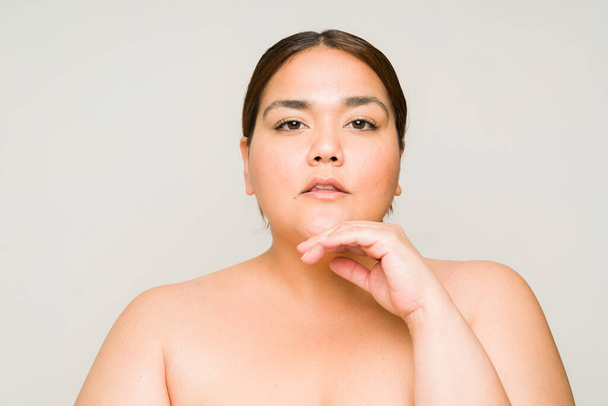 Портрет красивої латиноамериканки плюс розмір жінки з голими плечима, що показує м'яку здорову шкіру і концепцію краси  - Фото, зображення