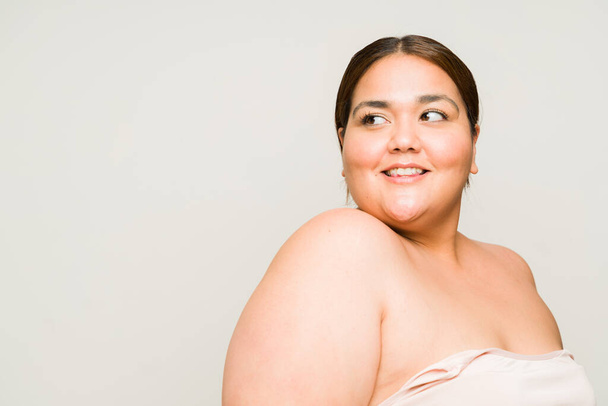 Cheerful plus size woman smiling feeling beautiful and with a lot of self love with soft skin next to copy space - Photo, Image