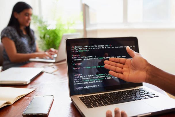 Over de schouder van de jonge mannelijke ontwikkelaar gebaar te coderen op laptop in het kantoor. Hoge kwaliteit foto - Foto, afbeelding