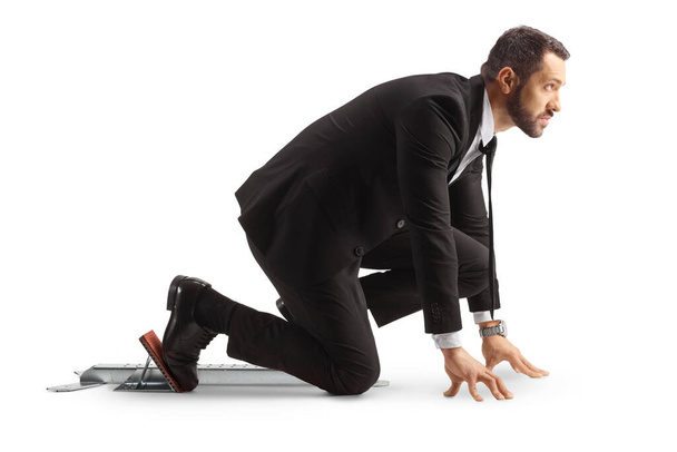 Full length profile shot of a businessman preparing for a run on starting blocks isolated on white background - Φωτογραφία, εικόνα
