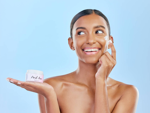 Face, cream in hand and beauty, woman with skincare and cosmetics product isolated on blue background. Lotion, sunscreen and facial mask, smile and moisturizer with female model and dermatology. - Фото, зображення
