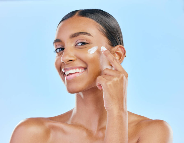 Face, cream and beauty, woman in portrait with skincare and cosmetics product isolated on blue background. Lotion, sunscreen and facial mask, smile and moisturizer with female model and dermatology. - Фото, изображение