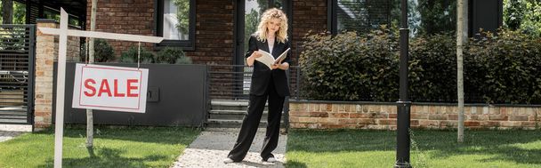 full length of blonde realtor with folder near cottage and signboard with for sale lettering, banner - Photo, Image