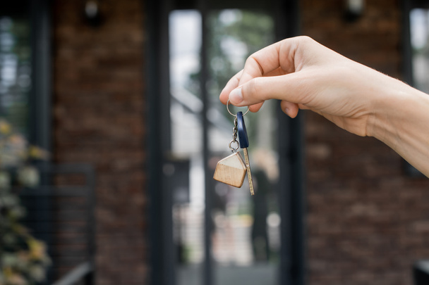 partial view of real estate agent holding key near new city cottage on blurred background - Photo, Image