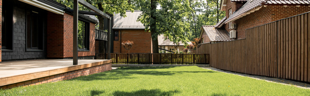 Gemütliches Haus mit Patio, grünem Rasen, Holzzaun, Hüttenstadt, Immobilienmarkt, Banner - Foto, Bild