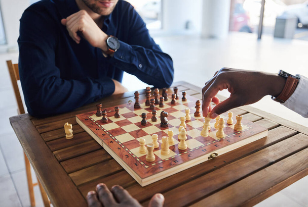 Manos, competencia y personas con un juego de ajedrez, estrategia y jugar juntos por diversión. Mesa, profesional y amigos con un tablero para juegos, aprendizaje y experto con una habilidad o pasatiempo en una habitación. - Foto, imagen