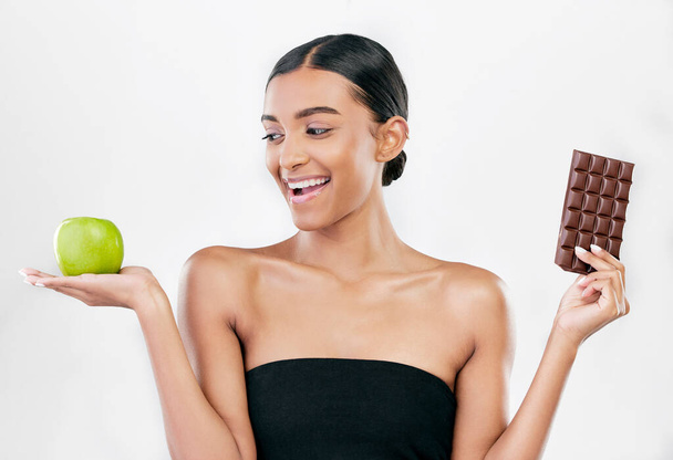 Apple, chocolate and happy woman for healthy food choice, sugar and skincare isolated on studio, white background. Dessert, green fruit and african person detox, vegan beauty or dermatology decision. - Foto, Bild