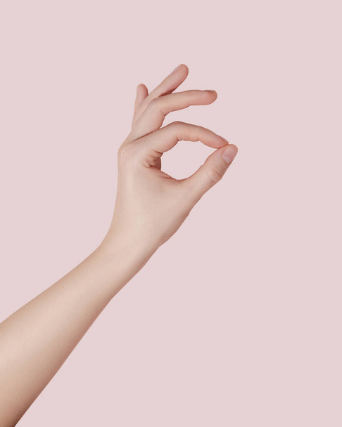 Женская рука делает хороший знак на розовом фоне.  - Фото, изображение