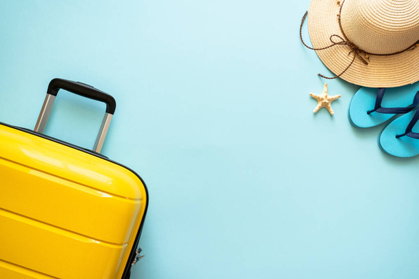 Suitcase, hat and flip flops on blue background. Happy Holidays, travel concept. - Photo, Image