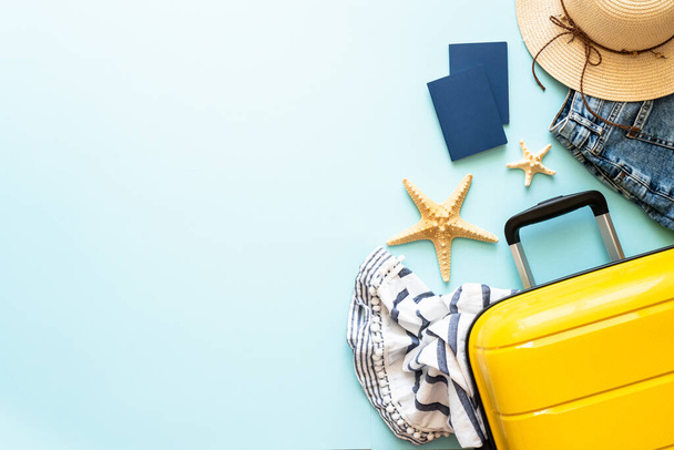 Koffer, paspoorten, hoed en zomerkleed op blauwe achtergrond. Prettige feestdagen, reisconcept. Vlakke lay afbeelding. - Foto, afbeelding