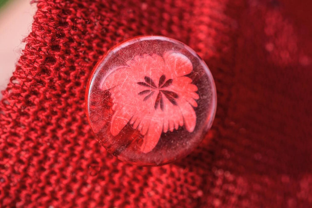 egy szürke kerek műanyag gomb mintával egy piros gyapjú szövet ruhák - Fotó, kép