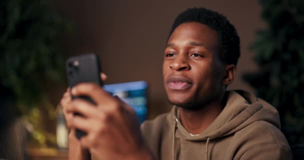 Podcast Anfitrión hombre afroamericano utilizando el teléfono celular para grabar anfitrión podcast animadas conversaciones, entrevistas invitados comparte contenido perspicaz mientras expresa entusiasmo a través de sonrisas bailando. - Imágenes, Vídeo