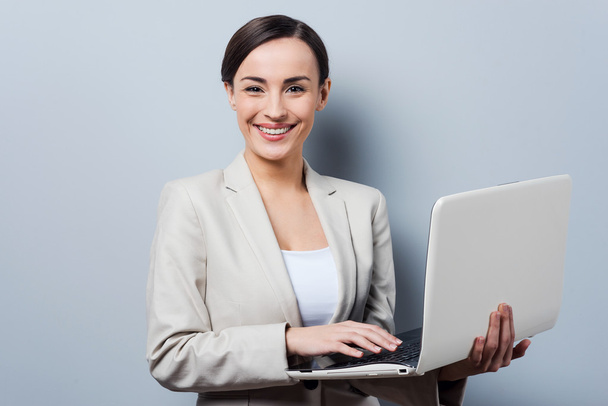 Businesswoman holding laptop and smiling - Photo, image