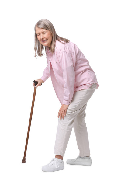 Senior woman with walking cane suffering from knee pain on white background - Foto, imagen