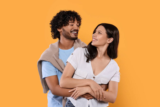 International dating. Happy couple hugging on yellow background - Foto, imagen