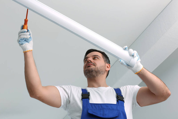 Ceiling light. Electrician installing led linear lamp indoors, low angle view - Foto, Imagen