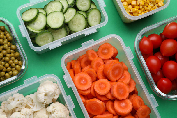 Plastic containers with different fresh products on green background, flat lay - Zdjęcie, obraz