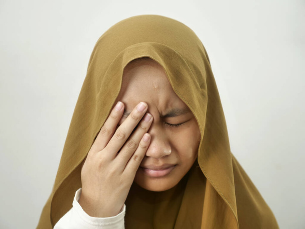 Asian muslim teenage girl wearing hijab crying and close her eye, depression or sore eyes concept - Фото, изображение