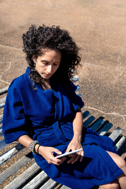 Güneşli bir günde dışarıda otururken kitap okuyan bir kadın. Teknoloji ve tatil kavramı. - Fotoğraf, Görsel