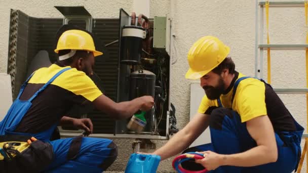Knowleadgeable engineers assembling professional pressure indicator to check liquids and gases in air conditioner. african american mechanic cleans layer of built up dirt and dust in condenser. - Footage, Video