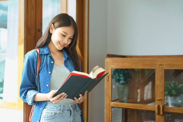 Education and literacy concept, College student smiling and standing to reading textbook. - Фото, изображение