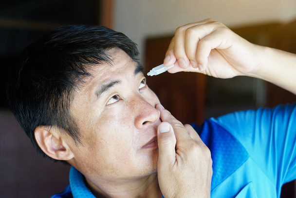 Hombre asiático utiliza lágrimas artificiales gotas de lubricante para los ojos con los ojos. Concepto, Salud. Tratamiento de los síntomas del ojo seco, enfermedades de la inflamación ocular. Alivio óptica irritada.          - Foto, imagen