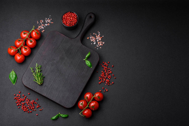 Ingrédients pour cuire les tomates cerises, le sel, les épices et les herbes sur un fond de béton foncé - Photo, image