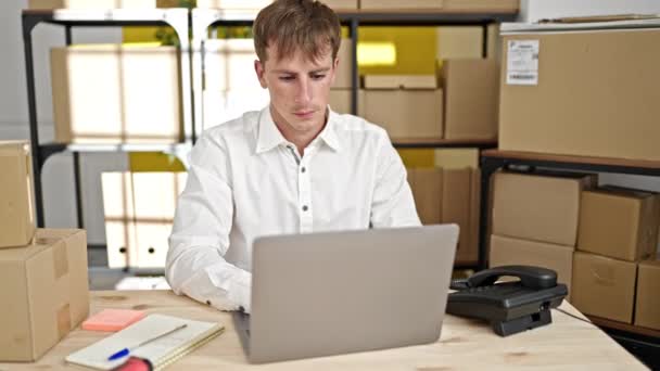 młody biały człowiek ecommerce biznes pracownik za pomocą laptop siedzi na stole w biuro - Materiał filmowy, wideo
