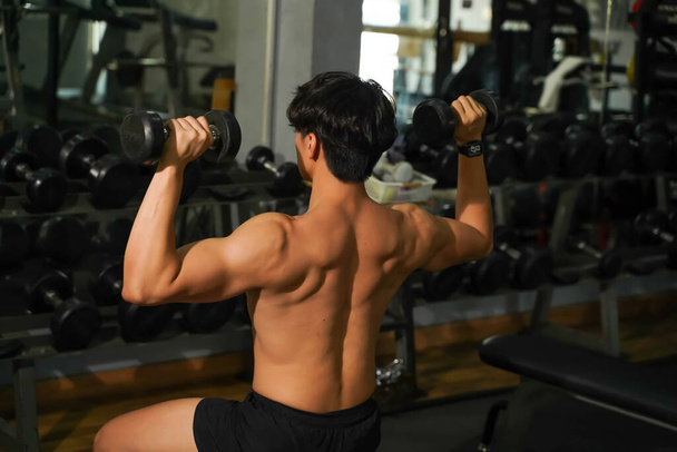 Closeup back view perfect body of Asian guy playing weight training at fitness center. - Photo, Image