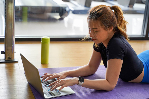 Lähikuva Aasian nuori nainen rentouttava pelata kannettava tietokone harjoittelun jälkeen ja jooga - Valokuva, kuva